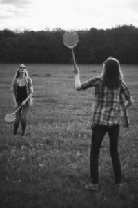 Two women playing badminton because of anxious attachment.