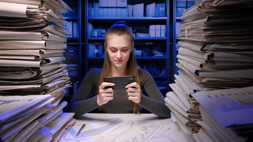A woman playing games first before doing her work because of self-sabotage psychology.