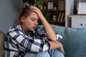 A woman holding her head, showing stress, intrusive thoughts, anxiety, and mental health struggles.
